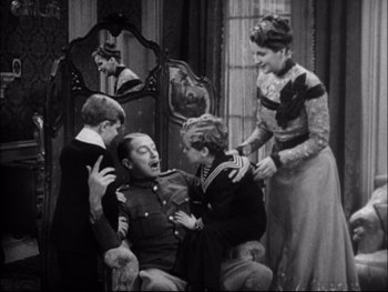 Movie still from “Cavalcade” (1933), directed by Frank Lloyd – A group of people standing around a man in a military uniform; Medium shot, High angle