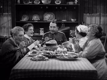 Movie still from “Cavalcade” (1933), directed by Frank Lloyd – A group of people sitting around a table eating; Medium shot, High angle