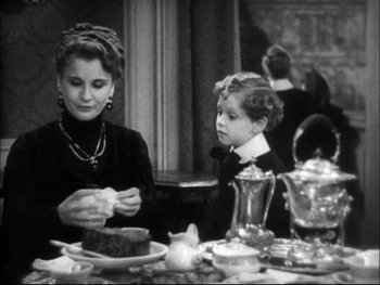 Movie still from “Cavalcade” (1933), directed by Frank Lloyd – A woman and a child sitting at a table; Medium shot, High angle