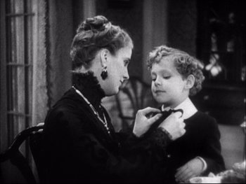 Movie still from “Cavalcade” (1933), directed by Frank Lloyd – An older woman adjusting a young boy's neck tie; Medium shot, High angle