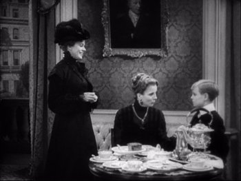 Movie still from “Cavalcade” (1933), directed by Frank Lloyd – An old photo of two women and a boy sitting at a table; Medium shot, High angle