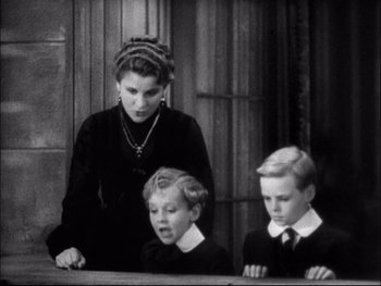 Movie still from “Cavalcade” (1933), directed by Frank Lloyd – A woman and two young boys are sitting at a table; Medium shot, High angle