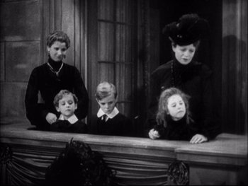 Movie still from “Cavalcade” (1933), directed by Frank Lloyd – An old black and white photo of a woman and three children; Medium shot, High angle