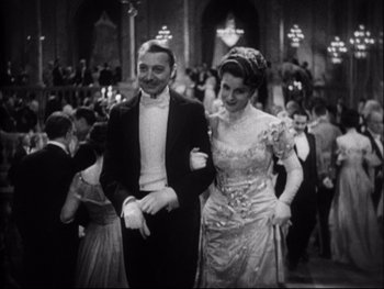 Movie still from “Cavalcade” (1933), directed by Frank Lloyd – A man and a woman in formal wear walking together; Medium shot, Low angle
