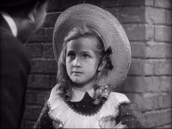 Movie still from “Cavalcade” (1933), directed by Frank Lloyd – A little girl wearing a straw hat standing in front of a brick wall; Close Up shot, High angle