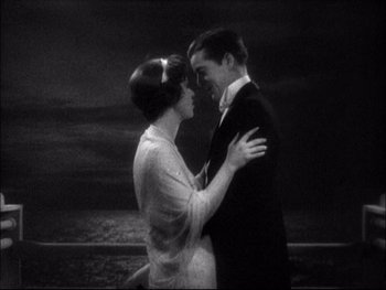 Movie still from “Cavalcade” (1933), directed by Frank Lloyd – A man and a woman embracing in front of a body of water; Medium shot, High angle