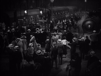 Movie still from “Cavalcade” (1933), directed by Frank Lloyd – A crowd of people standing on a street at night; Extreme Wide shot, High angle
