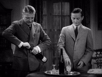 Movie still from “Cavalcade” (1933), directed by Frank Lloyd – Two men in suits are pouring wine into a glass; Medium shot, High angle