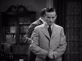 Movie still from “Cavalcade” (1933), directed by Frank Lloyd – A black and white photo of a man in a suit and tie; Medium shot, Over the shoulder angle