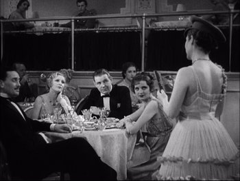 Movie still from “Cavalcade” (1933), directed by Frank Lloyd – A group of people sitting at a table with food; Medium shot, Over the shoulder angle