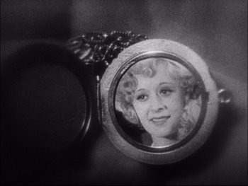 Movie still from “Cavalcade” (1933), directed by Frank Lloyd – A black and white photo of a woman's face in a locket; Close Up shot, High angle