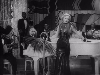 Movie still from “Cavalcade” (1933), directed by Frank Lloyd – An old black and white photo of a woman singing; Medium shot, High angle