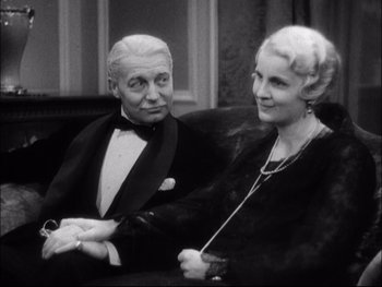 Movie still from “Cavalcade” (1933), directed by Frank Lloyd – An older man sitting next to an older woman on a couch; Medium shot, High angle