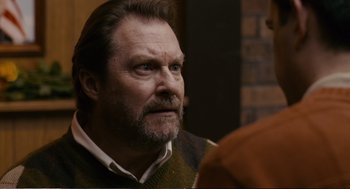 Movie still from “Cedar Rapids” (2011), directed by Miguel Arteta – A man with a beard and a sweater on looking at something; Close Up shot, Over the shoulder angle
