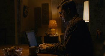 Movie still from “Cedar Rapids” (2011), directed by Miguel Arteta – A man sitting in front of a laptop computer; Medium shot, Low angle