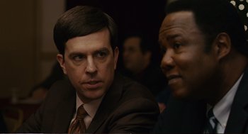 Movie still from “Cedar Rapids” (2011), directed by Miguel Arteta – A man in a suit and tie sitting next to another man in a suit and tie; Close Up shot, Over the shoulder angle