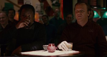 Movie still from “Cedar Rapids” (2011), directed by Miguel Arteta – Two men sitting at a table with a cigarette in their mouth; Medium shot, Over the shoulder angle