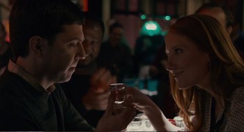 Movie still from “Cedar Rapids” (2011), directed by Miguel Arteta – A man and a woman sitting in front of each other holding drinks; Close Up shot, Over the shoulder angle