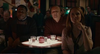 Movie still from “Cedar Rapids” (2011), directed by Miguel Arteta – A group of people sitting at a table with drinks; Medium shot, Over the shoulder angle