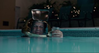 Movie still from “Cedar Rapids” (2011), directed by Miguel Arteta – A man with a helmet on his head drinking a glass of water; Medium shot, Overhead angle