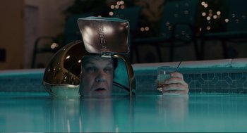 Movie still from “Cedar Rapids” (2011), directed by Miguel Arteta – A man sitting in a swimming pool with a laptop on his head; Medium shot, Overhead angle