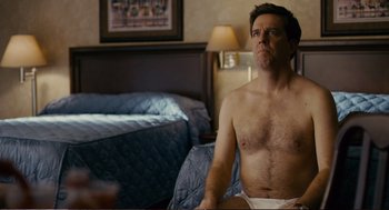Movie still from “Cedar Rapids” (2011), directed by Miguel Arteta – A man sitting on top of a bed in his underwear; Medium shot, Over the shoulder angle