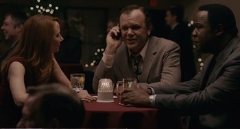 Movie still from “Cedar Rapids” (2011), directed by Miguel Arteta – A man in a suit talking on a cell phone at a table; Medium shot, Over the shoulder angle