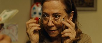 Movie still from “Central Station” (1998), directed by Walter Salles – An older woman wearing glasses and a pair of headphones; Close Up shot, Over the shoulder angle