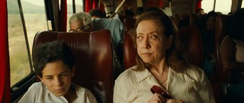 Movie still from “Central Station” (1998), directed by Walter Salles – An older woman sitting on a bus holding a cell phone; Close Up shot, Over the shoulder angle