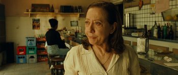 Movie still from “Central Station” (1998), directed by Walter Salles – An older woman in a white shirt in a restaurant; Close Up shot, Over the shoulder angle