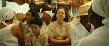 Movie still from “Central Station” (1998), directed by Walter Salles – An older woman sitting next to a group of people; Medium shot, Over the shoulder angle
