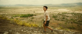 Movie still from “Central Station” (1998), directed by Walter Salles – A young man is walking on a dirt hill; Wide shot, Low angle