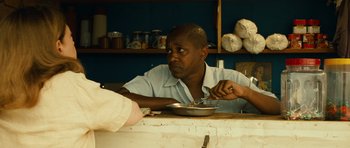 Movie still from “Central Station” (1998), directed by Walter Salles – A man sitting at a table with a bowl of food in front of him; Medium shot, Over the shoulder angle