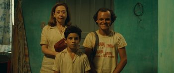Movie still from “Central Station” (1998), directed by Walter Salles – Three people are posing for a picture in front of a green wall; Medium shot, Low angle