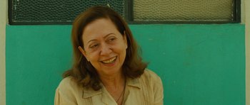 Movie still from “Central Station” (1998), directed by Walter Salles – A woman smiling for the camera in front of a green wall; Close Up shot, Over the shoulder angle