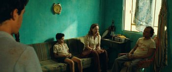 Movie still from “Central Station” (1998), directed by Walter Salles – A woman and a boy sitting on a couch in front of a wall clock; Medium shot, Over the shoulder angle
