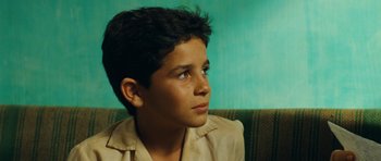 Movie still from “Central Station” (1998), directed by Walter Salles – A young boy sitting on a couch looking off to his right; Close Up shot, High angle