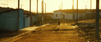 Movie still from “Central Station” (1998), directed by Walter Salles – A person walking down a dirt road near a building; Extreme Wide shot, Low angle