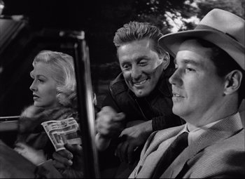 Movie still from “Champion” (1949), directed by Mark Robson – A group of people sitting next to each other on the street; Close Up shot, Over the shoulder angle