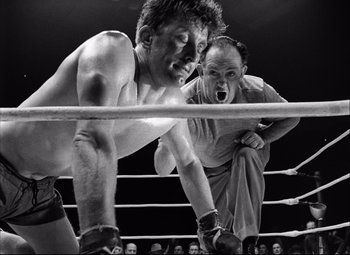 Movie still from “Champion” (1949), directed by Mark Robson – Two men in a boxing ring fighting in front of a crowd of people; Medium shot, Low angle