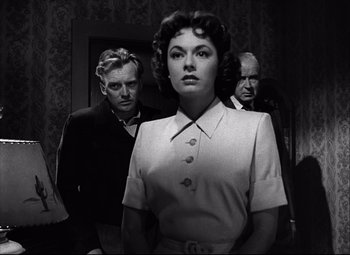 Movie still from “Champion” (1949), directed by Mark Robson – A black and white photo of a woman and two men; Medium shot, Low angle