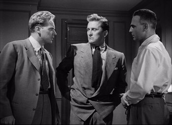 Movie still from “Champion” (1949), directed by Mark Robson – A group of men standing next to each other in a room; Medium shot, Low angle
