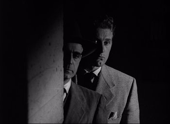 Movie still from “Champion” (1949), directed by Mark Robson – A man in a suit and tie next to another man in a suit and tie; Close Up shot, Low angle