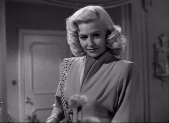 Movie still from “Champion” (1949), directed by Mark Robson – A black - and - white photo of a woman holding a dandelion; Close Up shot, Low angle