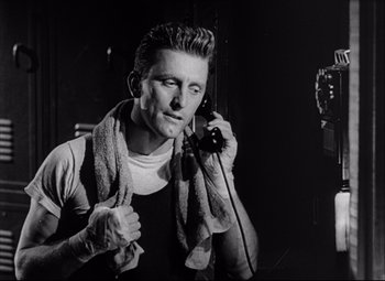 Movie still from “Champion” (1949), directed by Mark Robson – A black and white photo of a man talking on a phone; Close Up shot, Low angle