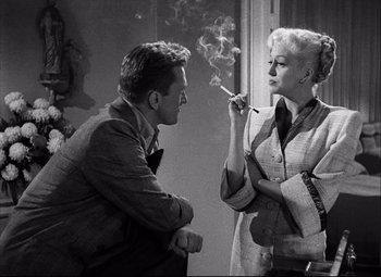 Movie still from “Champion” (1949), directed by Mark Robson – A man and a woman are smoking a cigarette together; Medium shot, Low angle