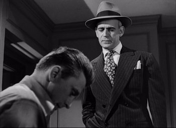 Movie still from “Champion” (1949), directed by Mark Robson – An old photo of a man in a suit and a hat; Medium shot, Low angle