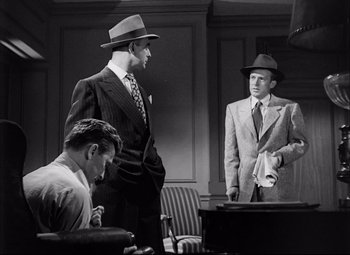 Movie still from “Champion” (1949), directed by Mark Robson – A group of men standing next to each other in a room; Medium shot, Low angle