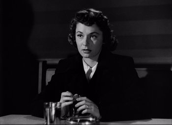 Movie still from “Champion” (1949), directed by Mark Robson – A woman sitting at a table with a drink in front of her; Close Up shot, Over the shoulder angle