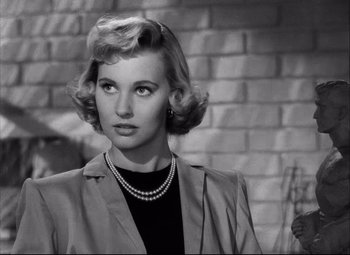 Movie still from “Champion” (1949), directed by Mark Robson – A black and white photo of a woman in a suit; Close Up shot, Over the shoulder angle